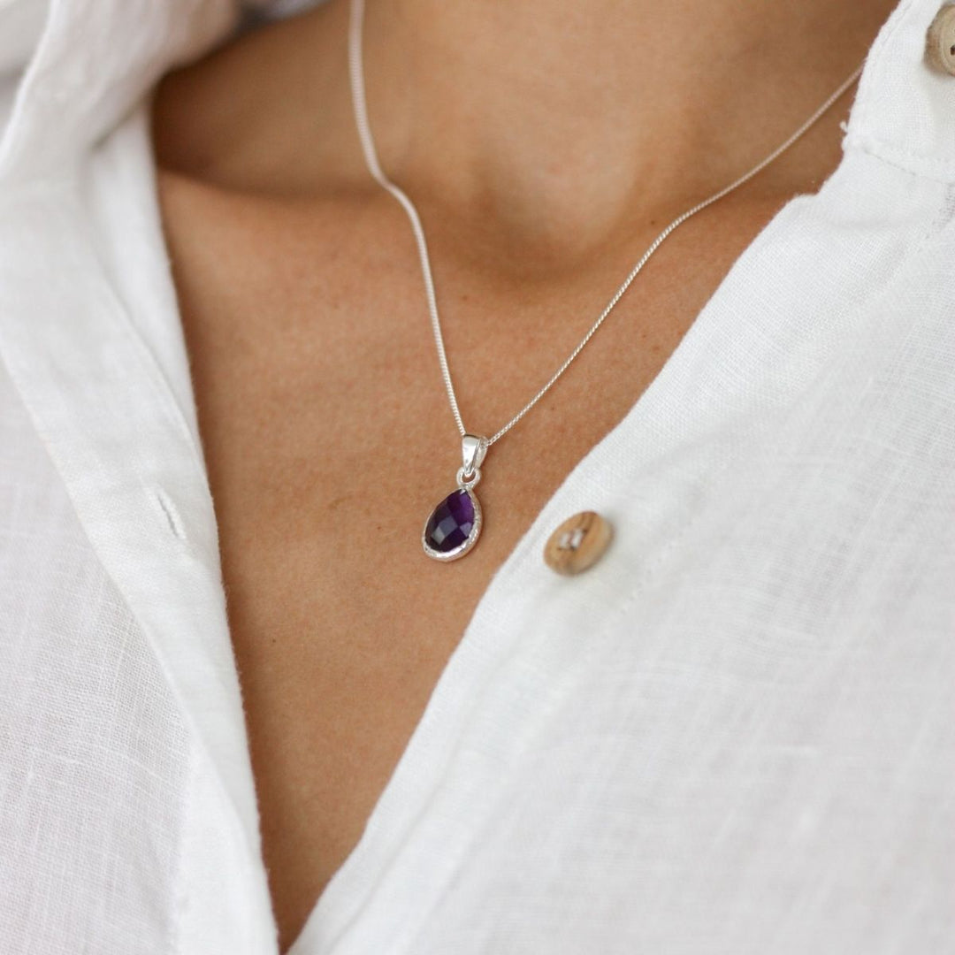 a woman wearing a purple pendant around her neck