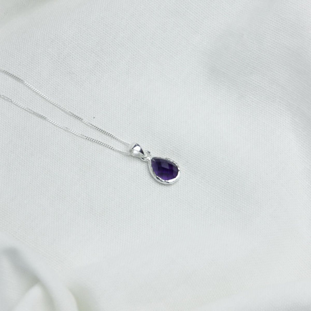 a purple pendant necklace on a white cloth