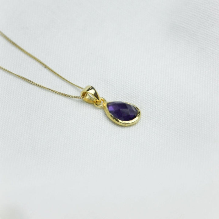 a purple pendant necklace on a white cloth
