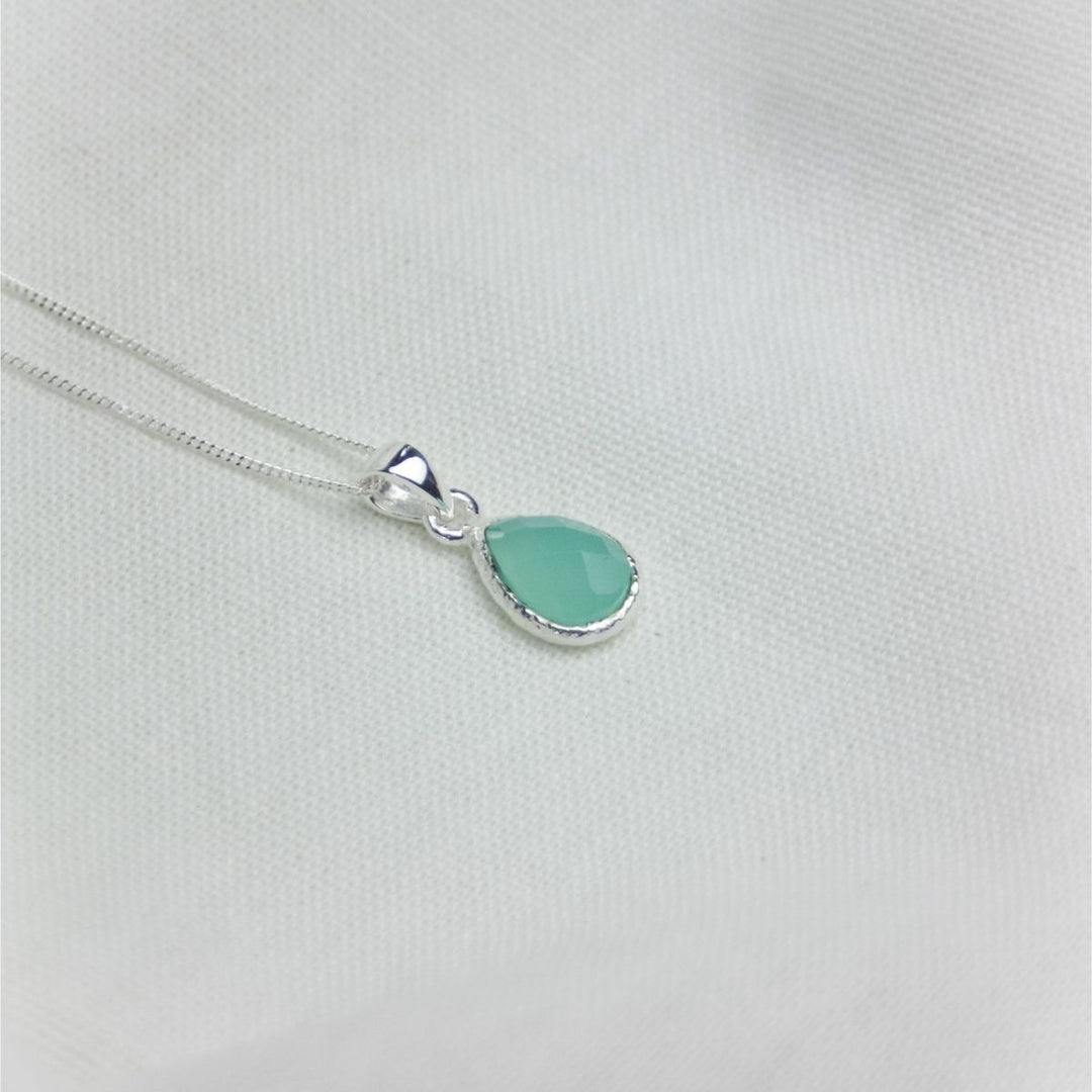 a blue pendant necklace on a white cloth