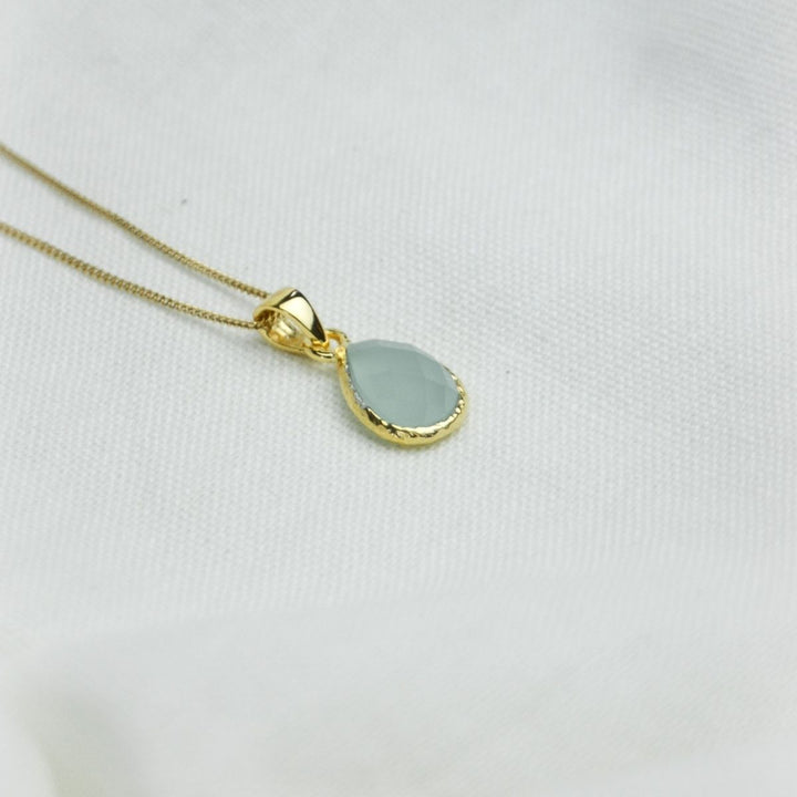 a blue pendant necklace on a white cloth