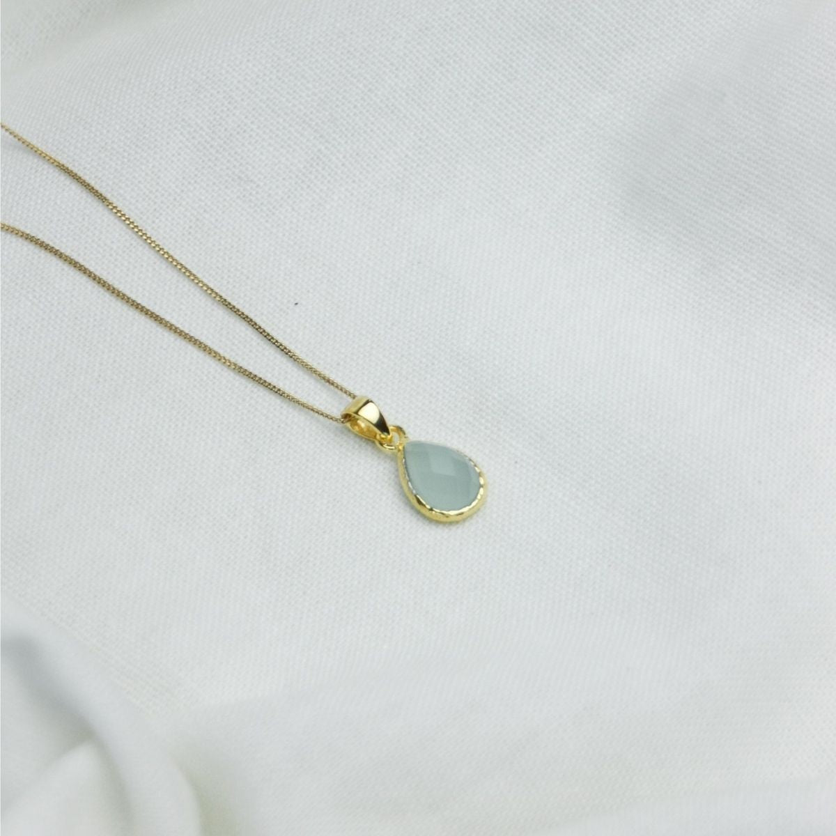 a blue pendant necklace on a white cloth