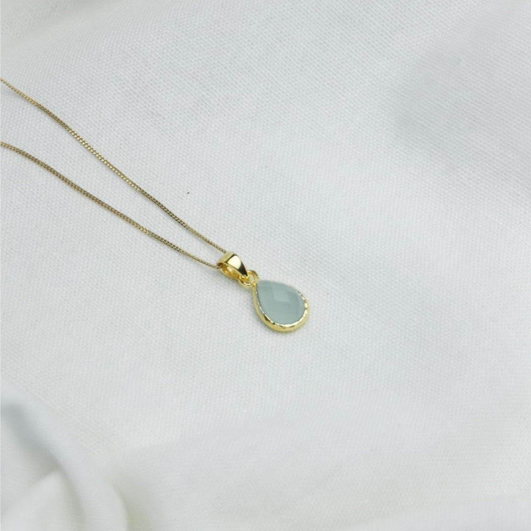 a blue pendant necklace on a white cloth