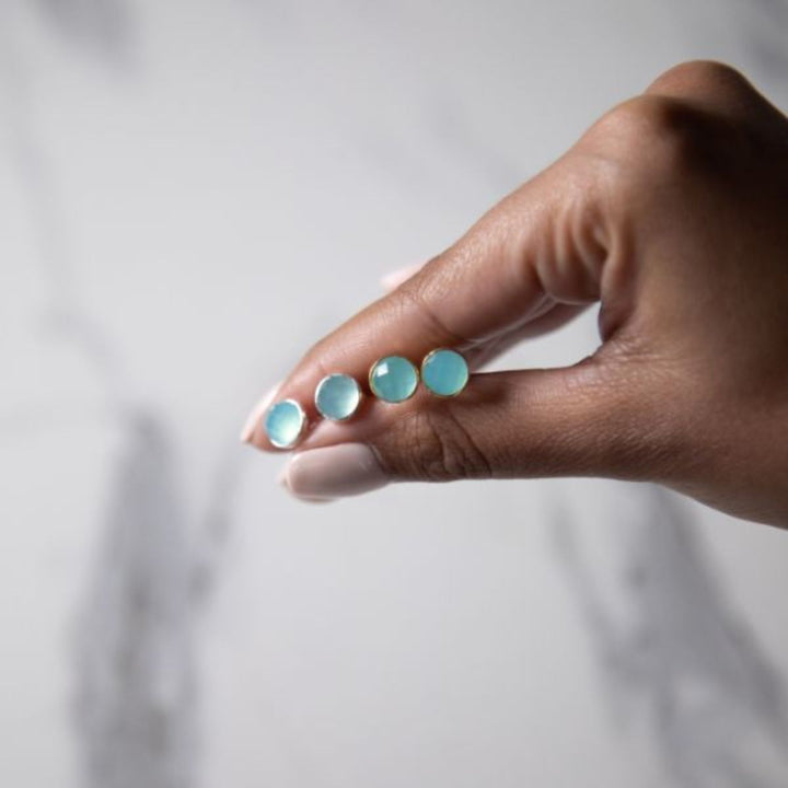 a woman holding two pairs of earrings in her hand 