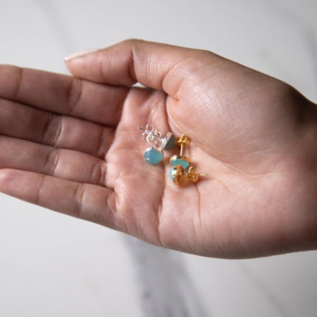 a woman holding to pairs of earrings in her hand