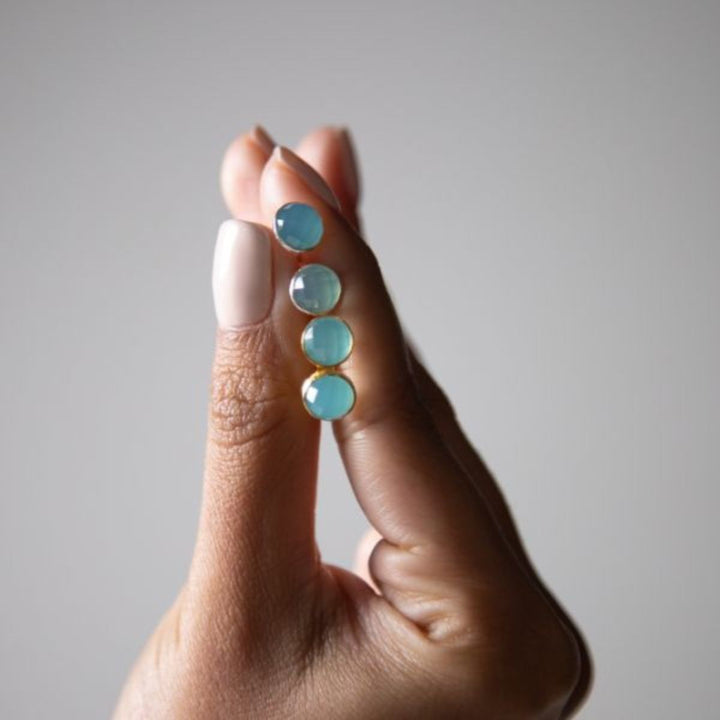 a woman holding two pairs of earrings in her hand 