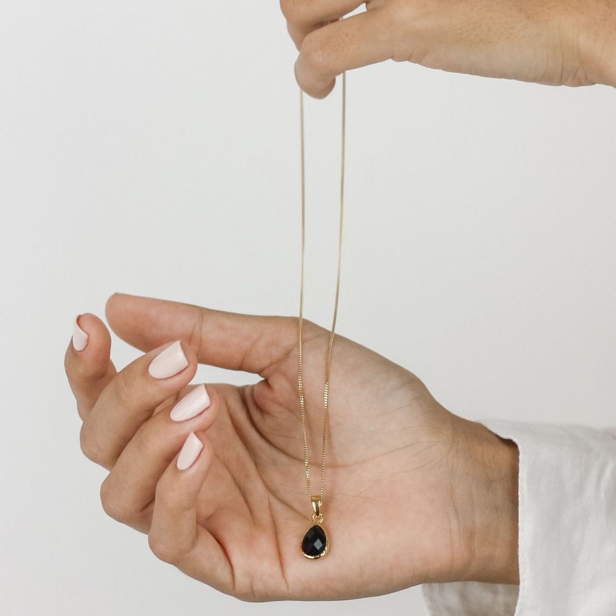 a woman holding a black pendant necklace in her hand 