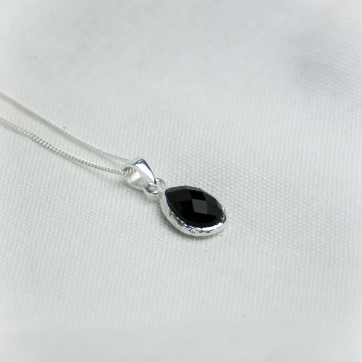 a black pendant necklace on a white sheet 