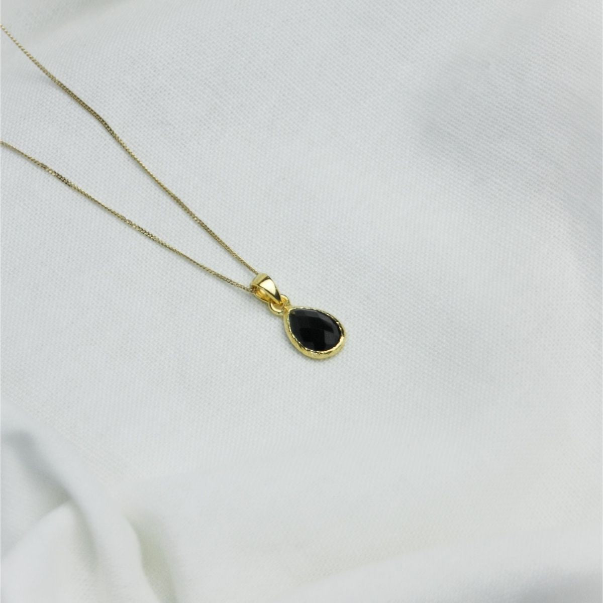 a black pendant necklace on a white sheet