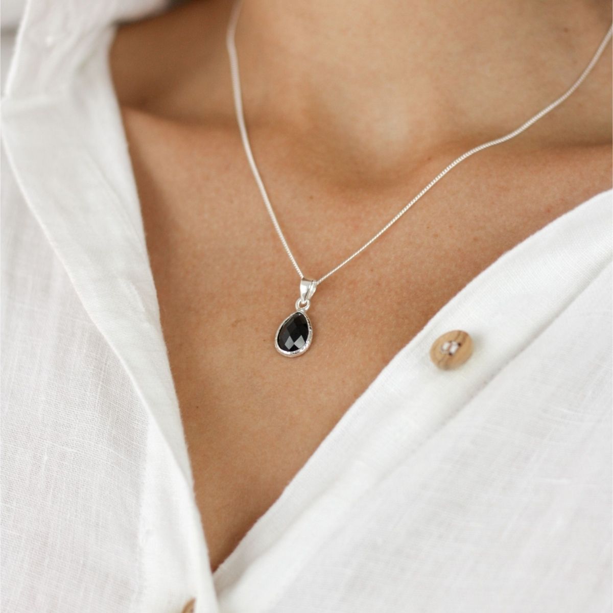 a woman wearing a black pendant necklace 