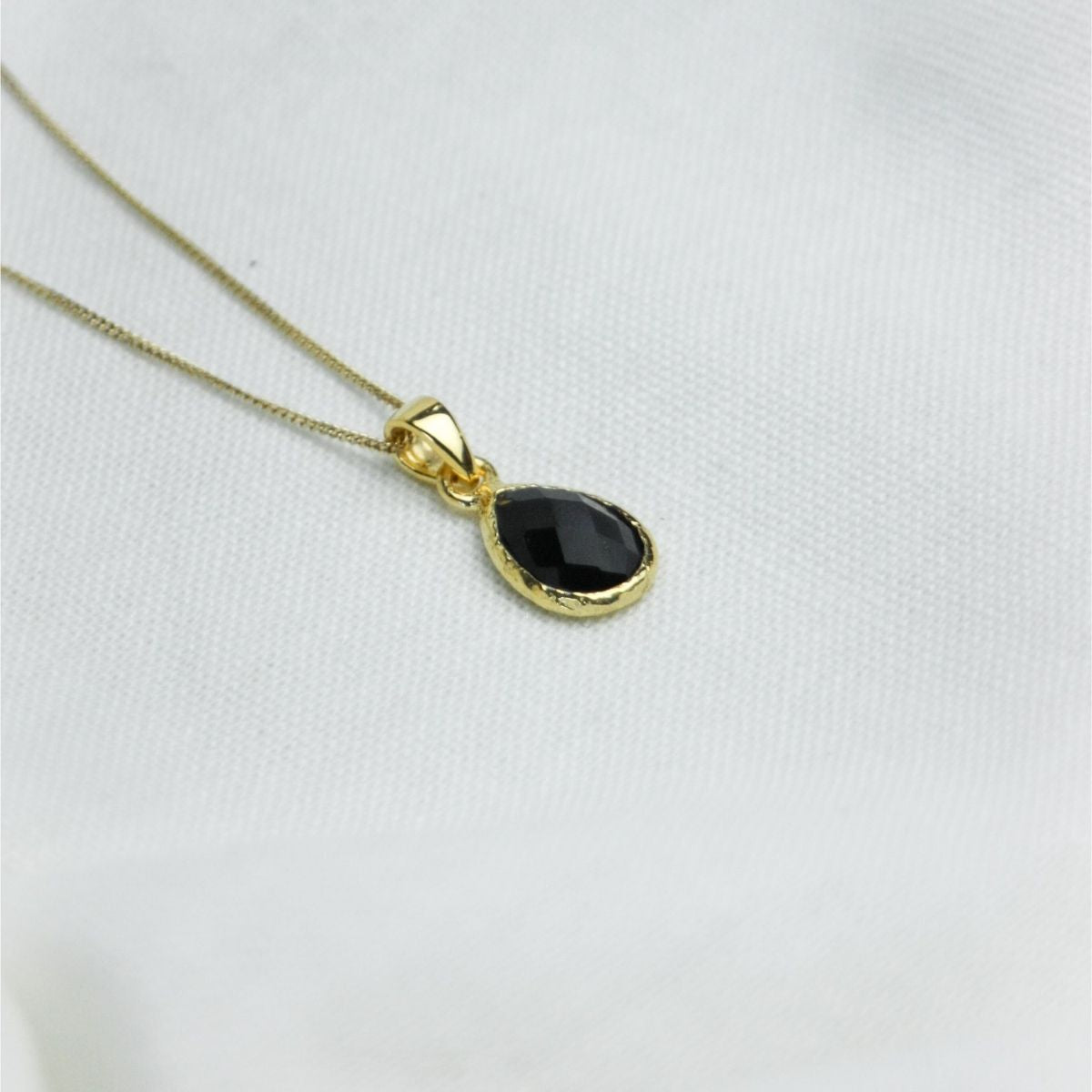 a black pendant necklace on a white cloth\