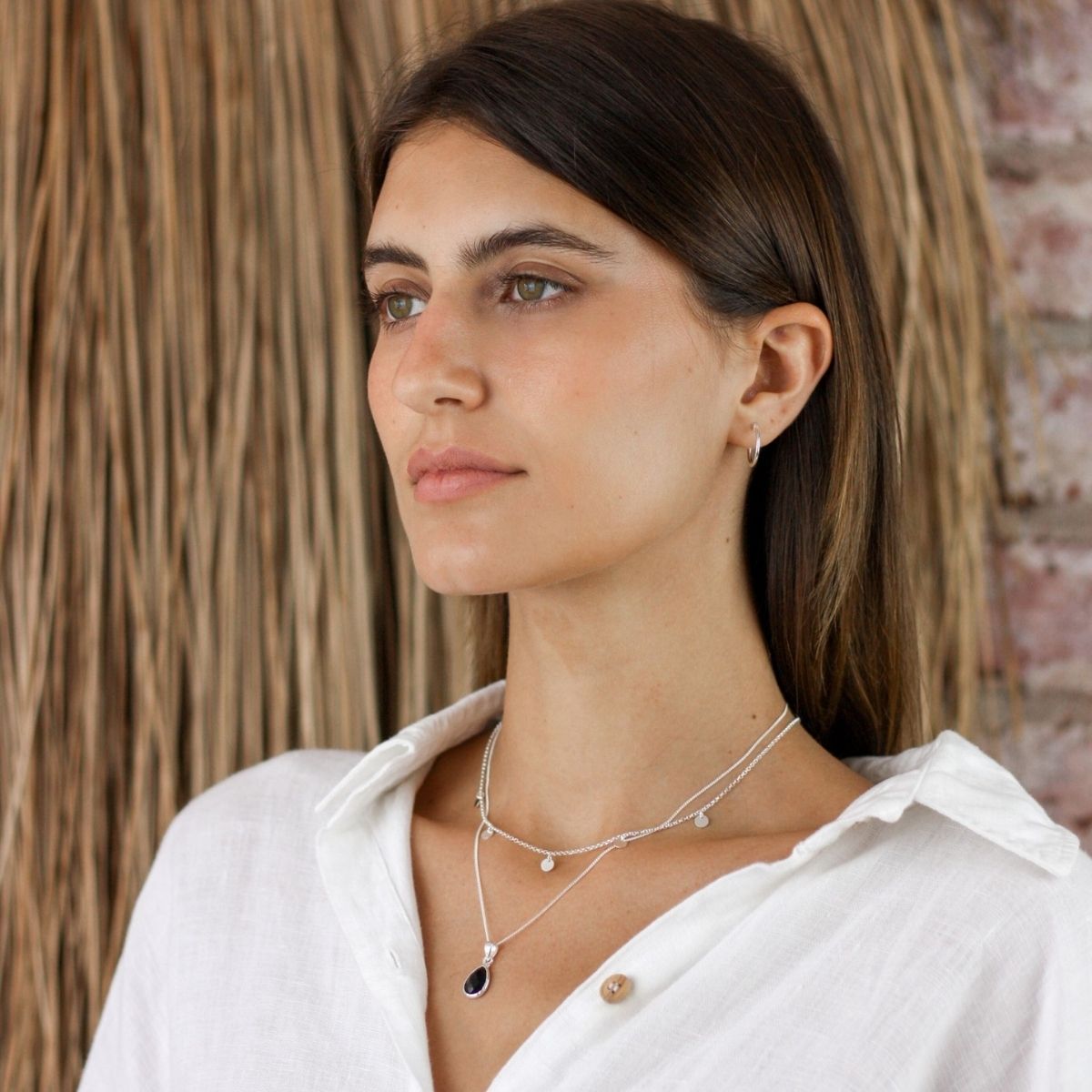 a woman wearing two necklaces around her neck