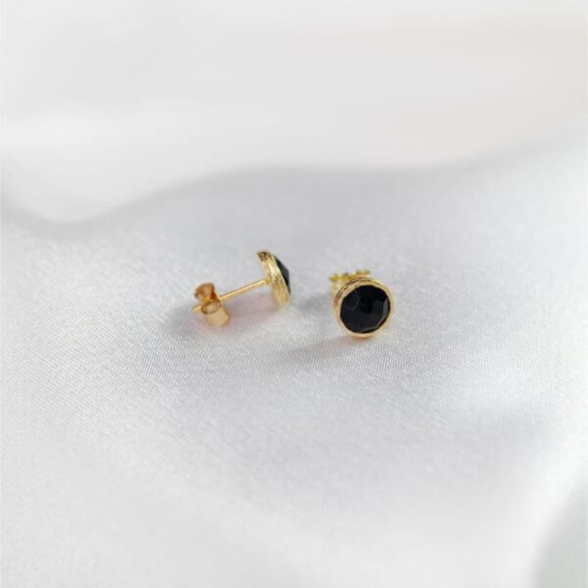 a pair of gold plated studs resting on a white cloth