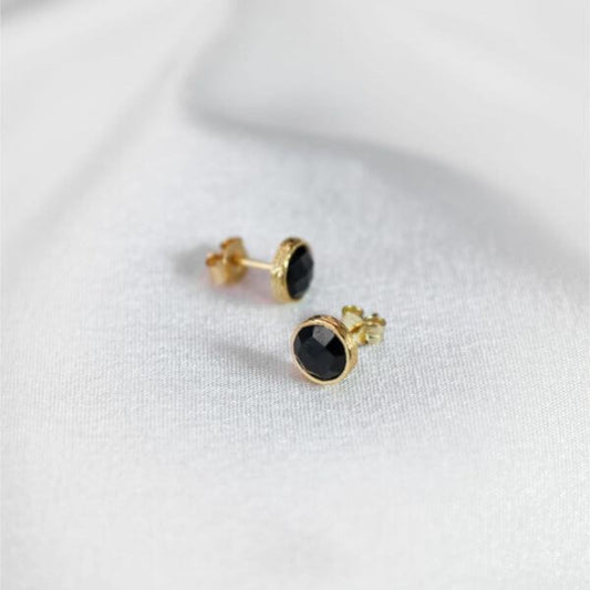 a pair of gold plated studs resting on a white cloth