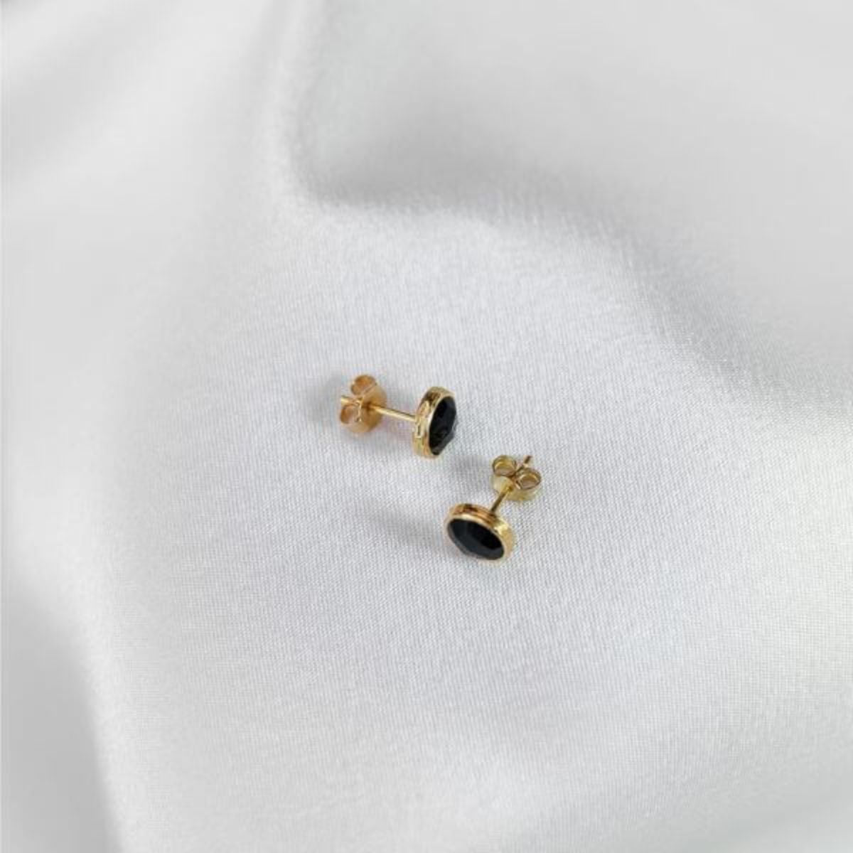 a pair of gold plated studs resting on a white cloth