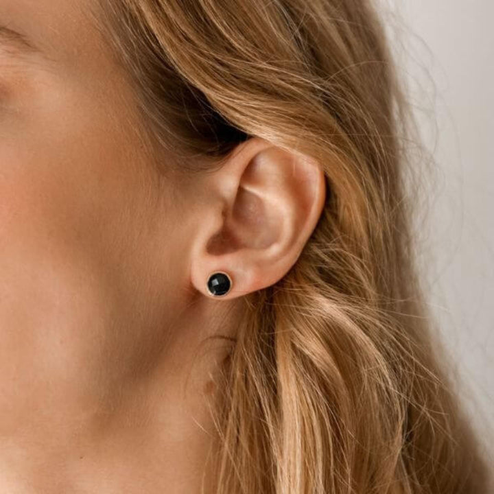 a woman wearing black onyx studs
