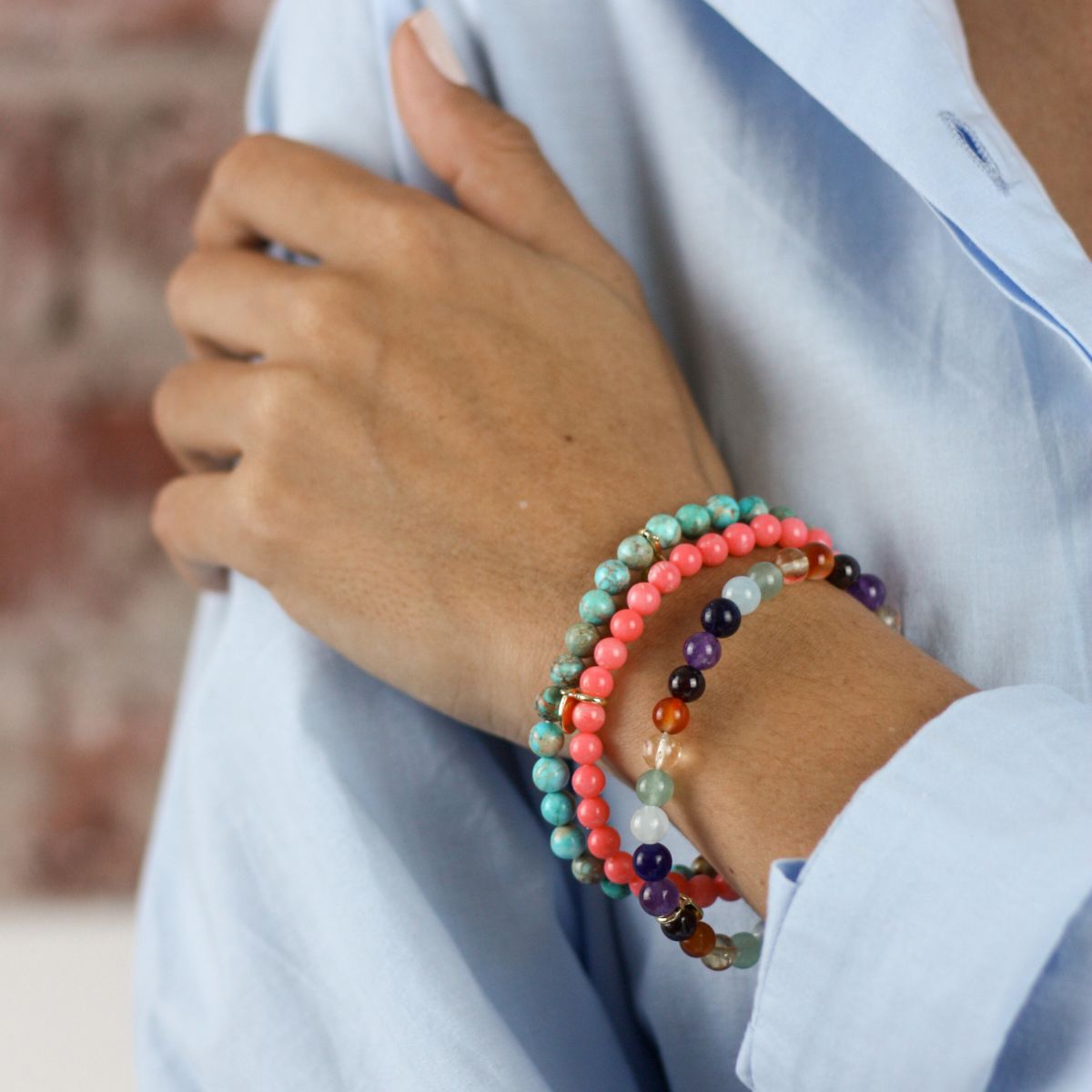 a woman wearing stacked bracelets on her wrist 