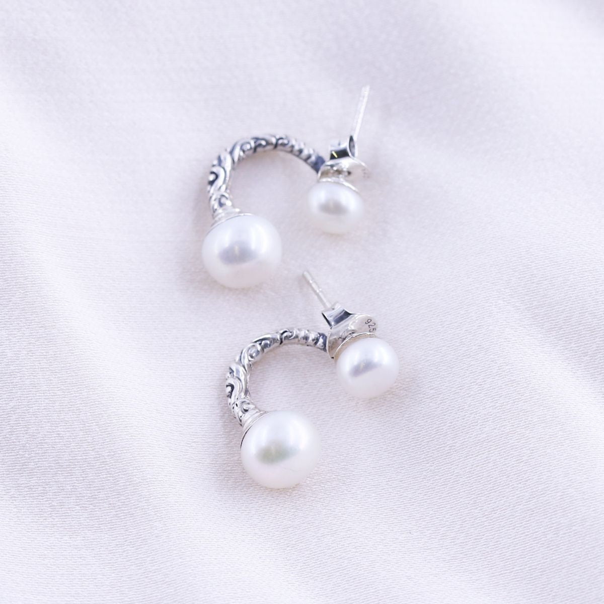 silver half hoop double pearl earrings on a white background