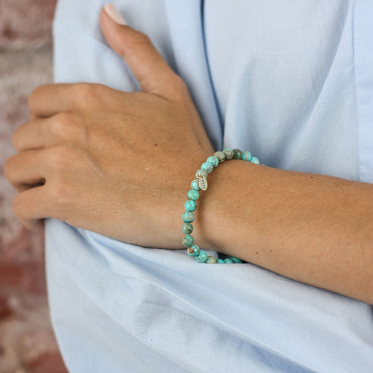 a woman wearing a stone bracelet on her wrist