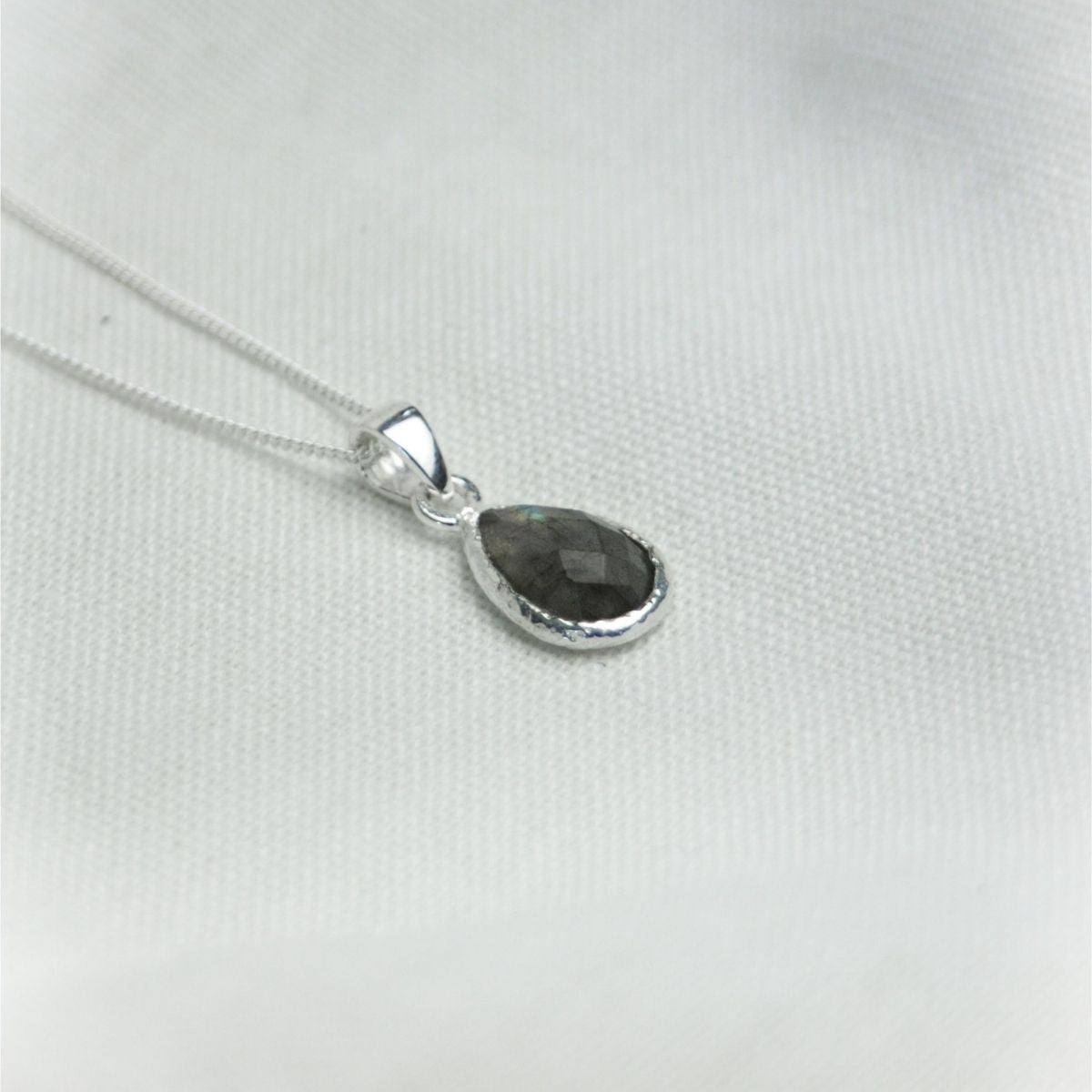 a pendant necklace on a white cloth