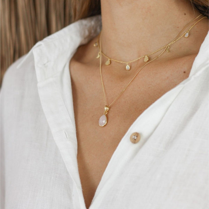 a woman wearing two necklaces around her neck