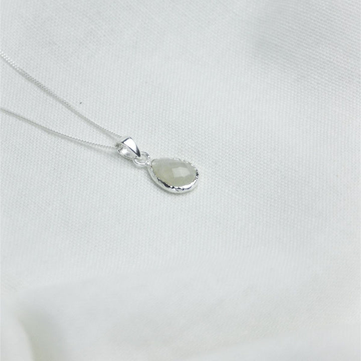 a white pendant necklace on a white cloth
