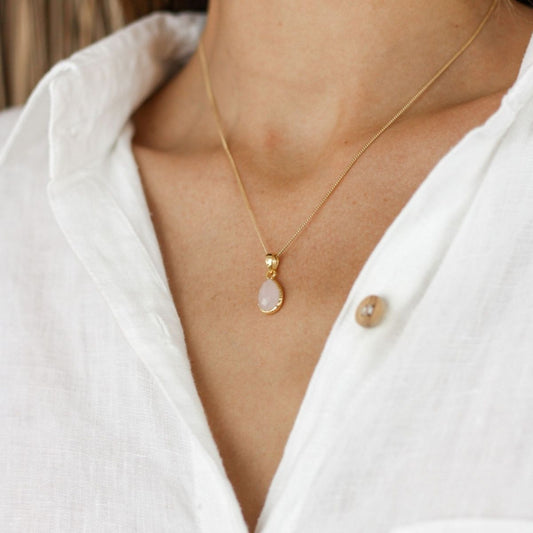 a woman wearing a white pendant necklace around her neck