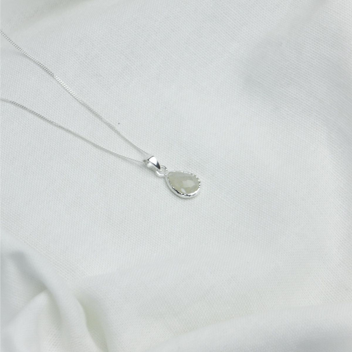 a white pendant necklace on  a white cloth