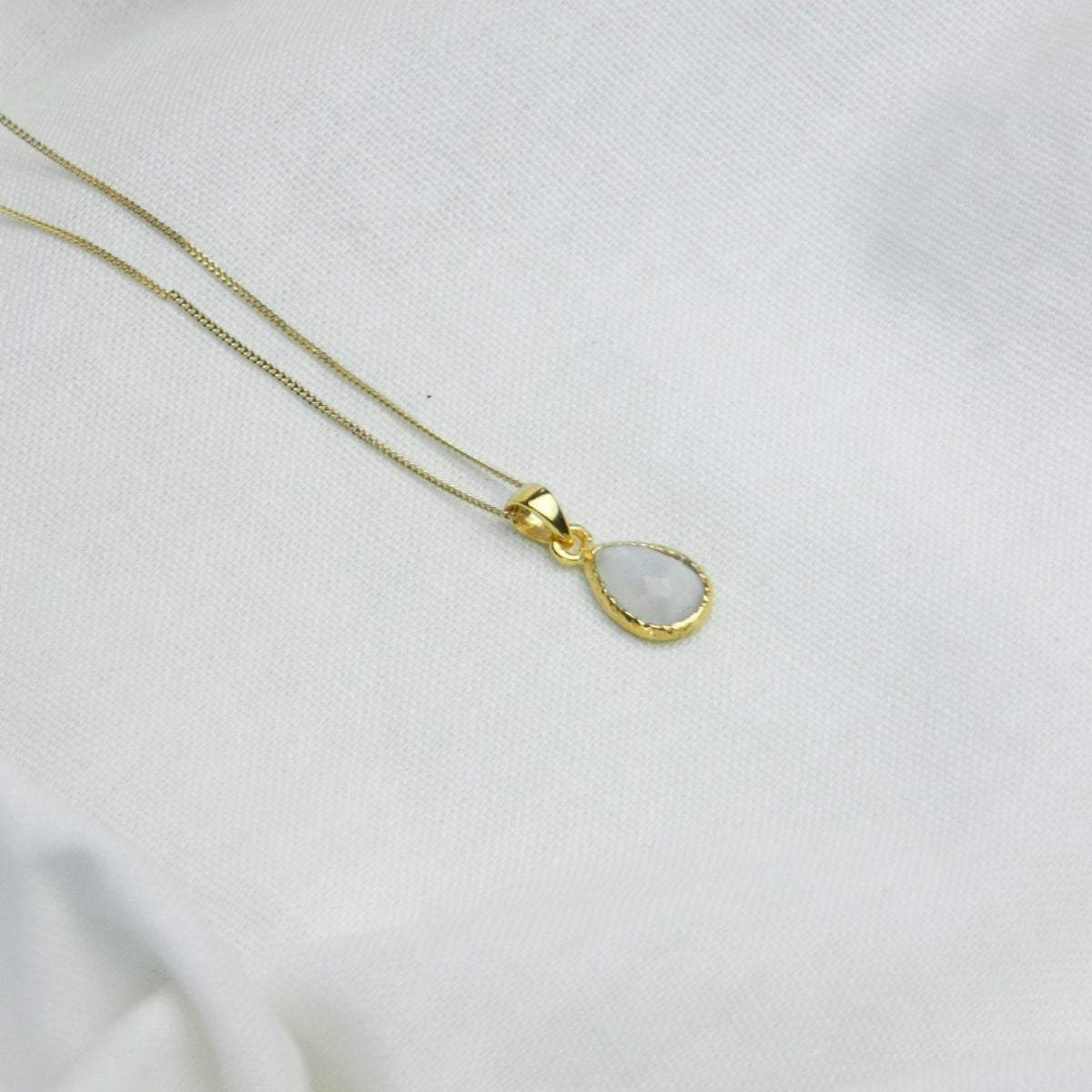 a white pendant necklace on a white cloth