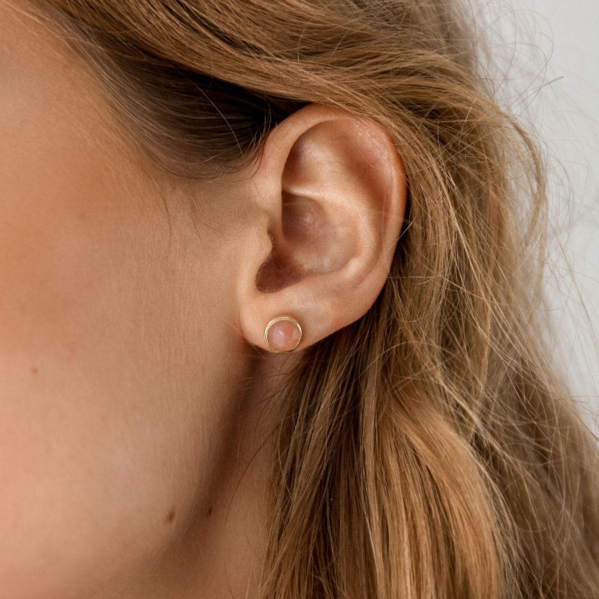a woman wearing peach moonstone studs in her ears