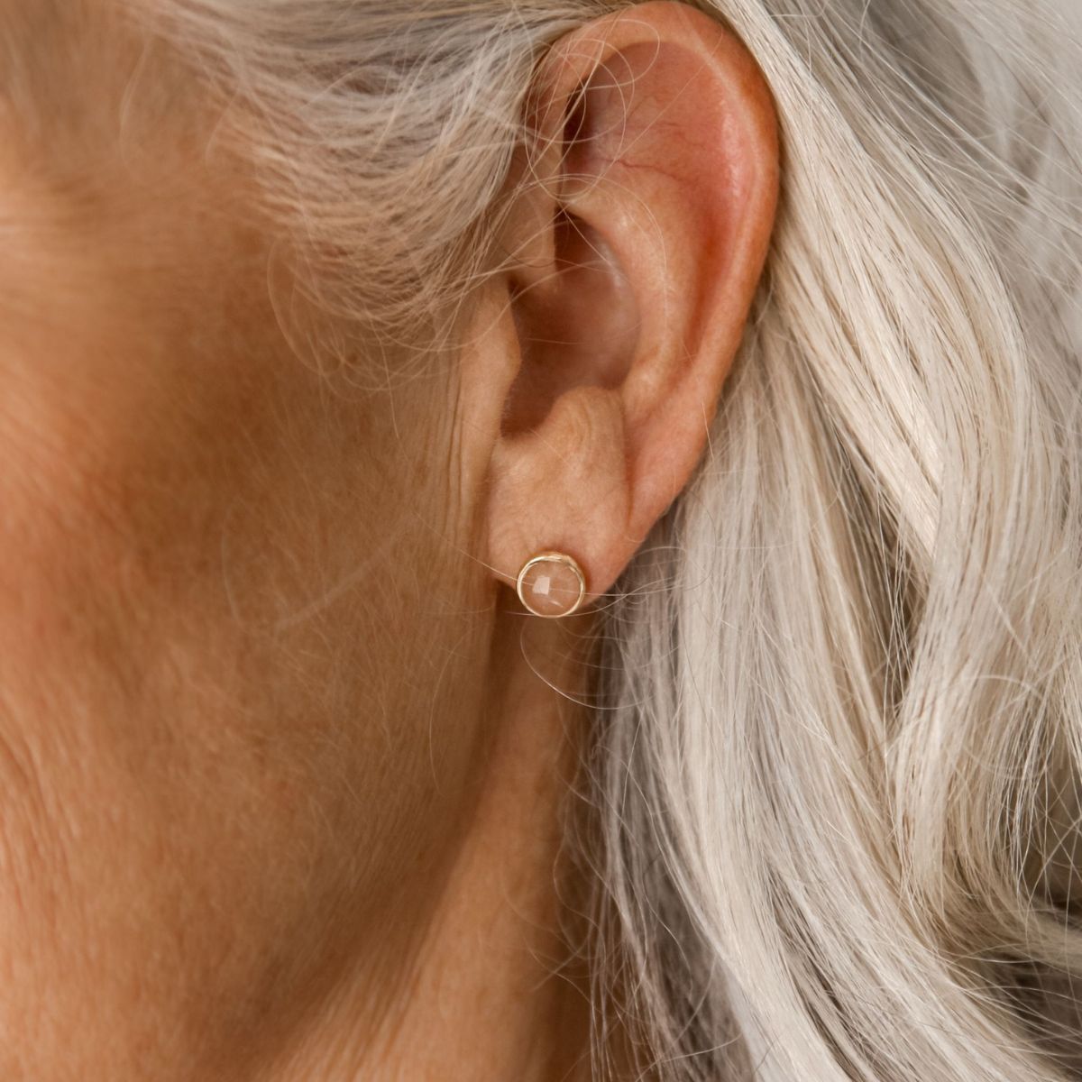 a woman wearing peach moonstone studs in her ear
