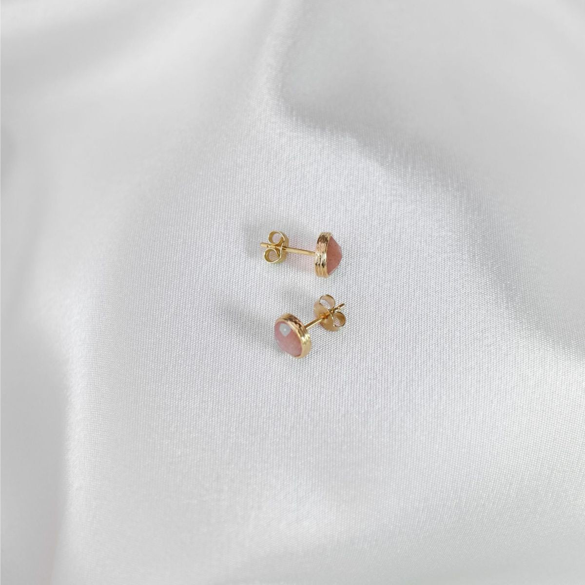a pair of peach moonstone studs on a white cloth