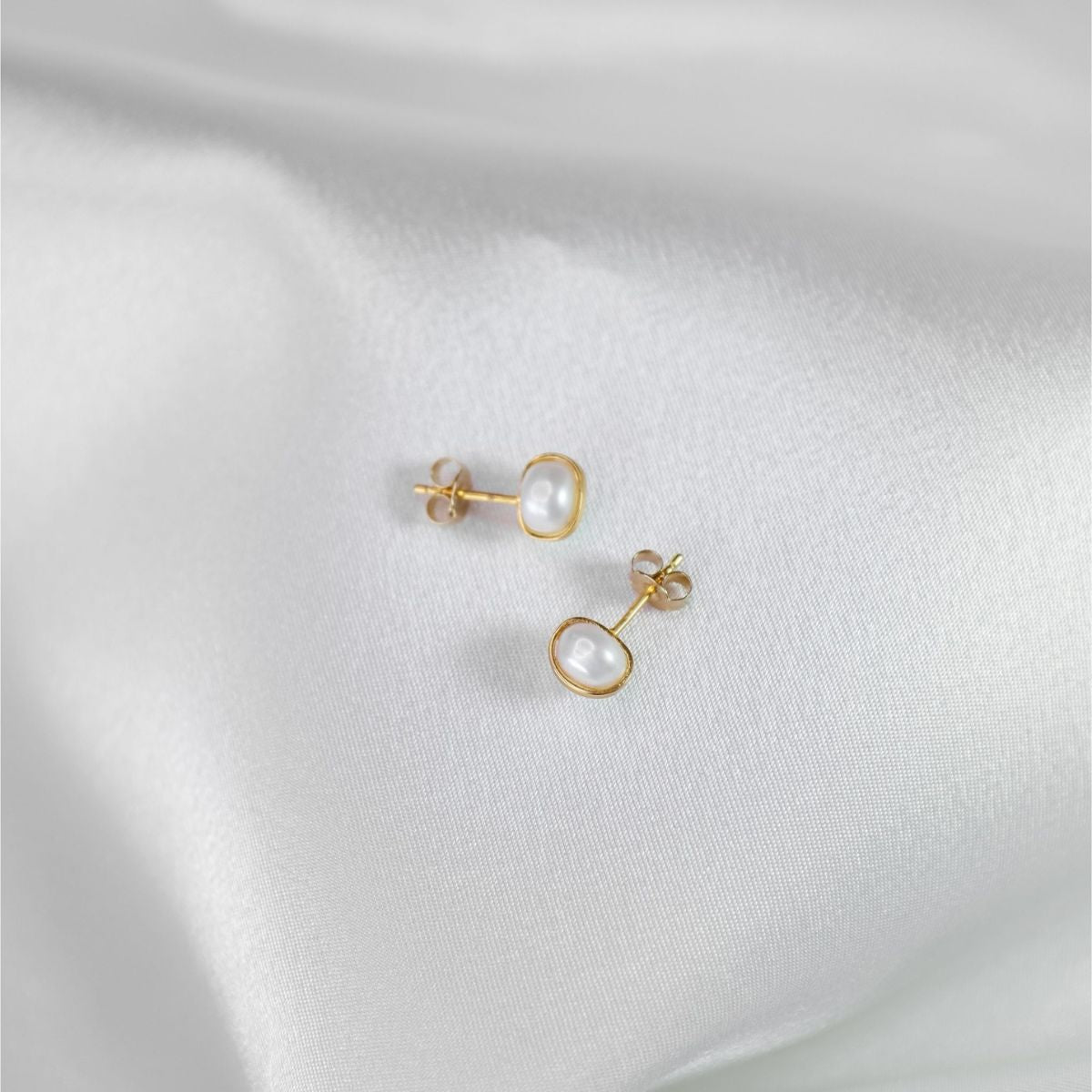 a pair of pearl earrings on a white cloth