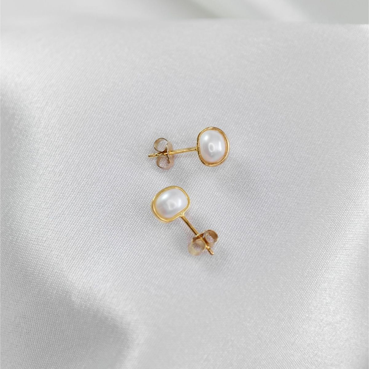 a pair of white pearl earrings on a white cloth