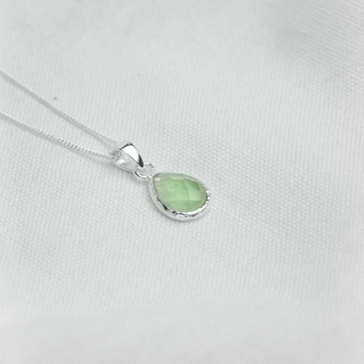 a pendant necklace on a white sheet