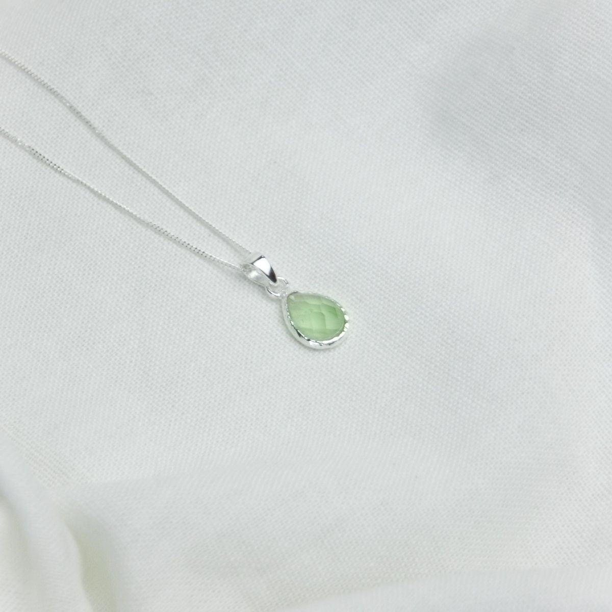 a pendant necklace on a white sheet