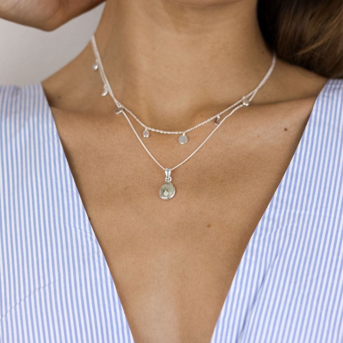 a woman wearing to necklaces around her neck