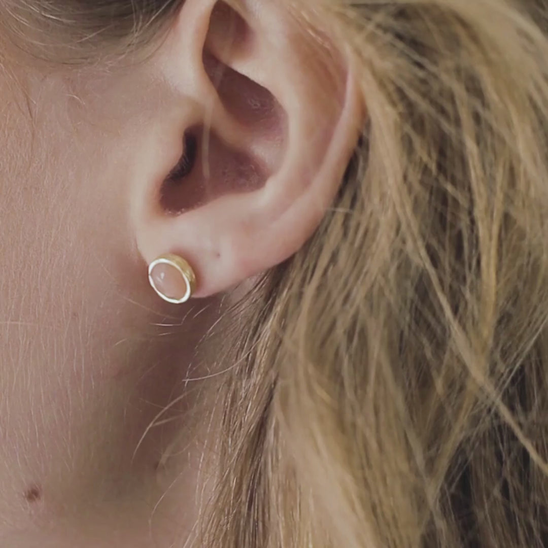 a woman wearing peach moonstone studs in her ears