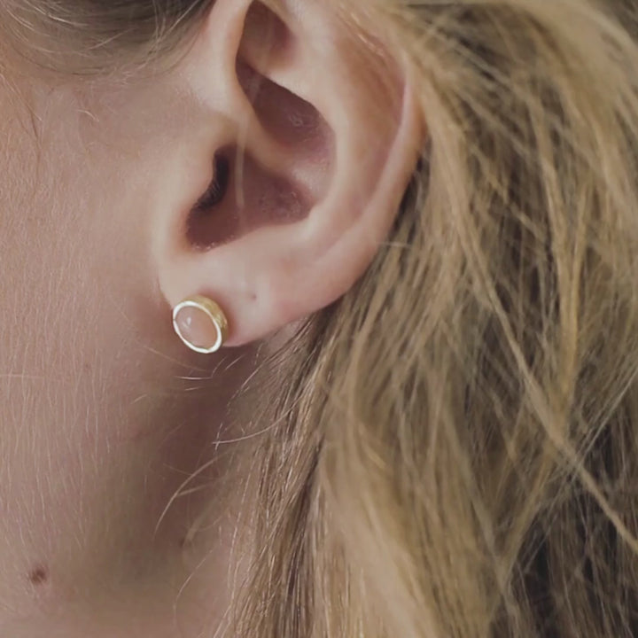 a woman wearing peach moonstone studs in her ears