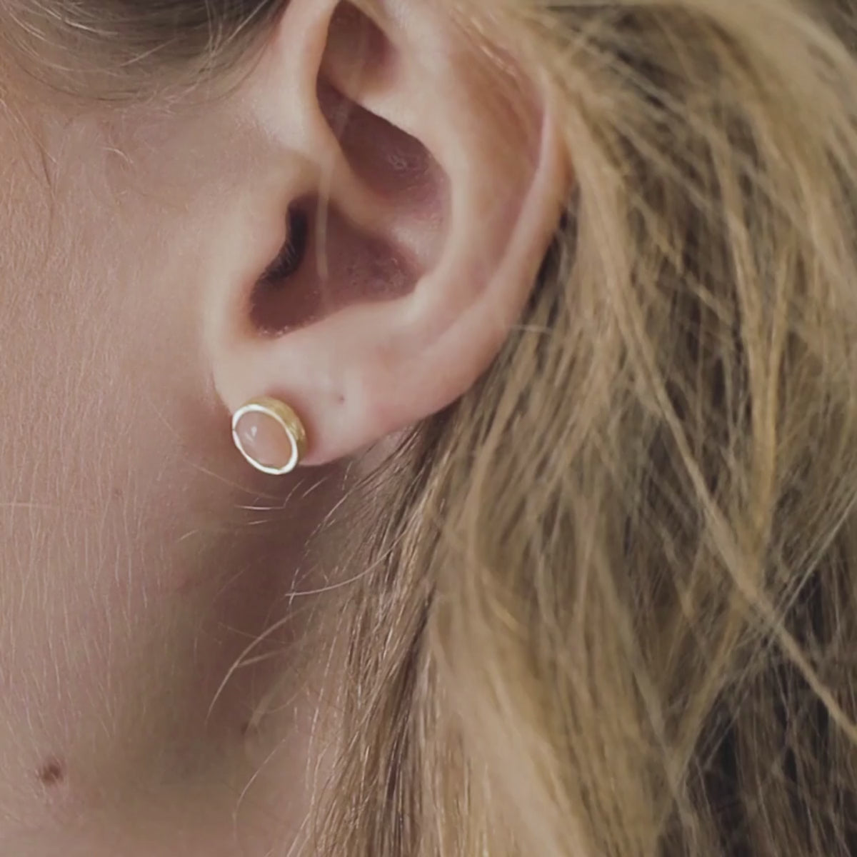 a woman wearing peach moonstone studs in her ears