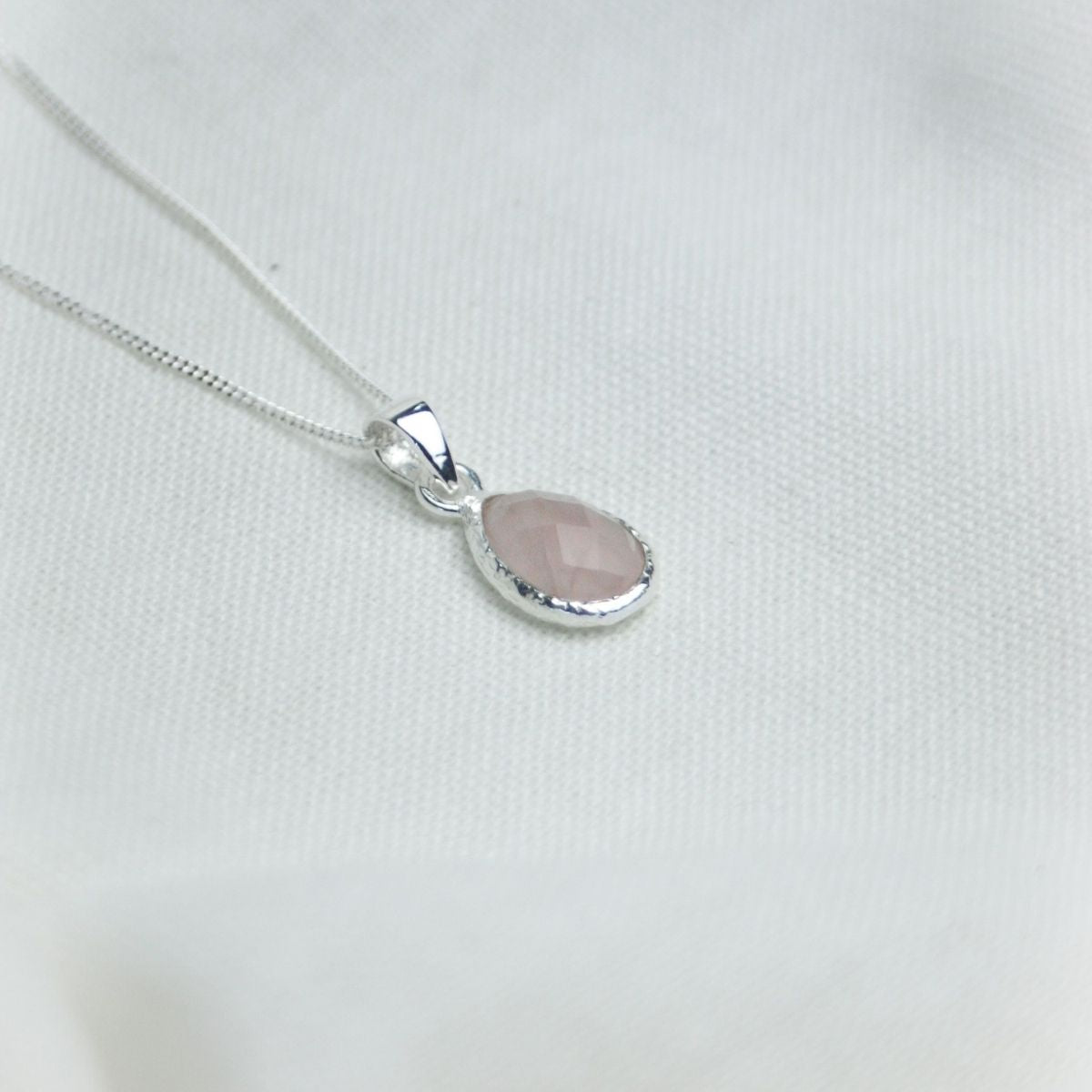 a pink pendant necklace on a white cloth