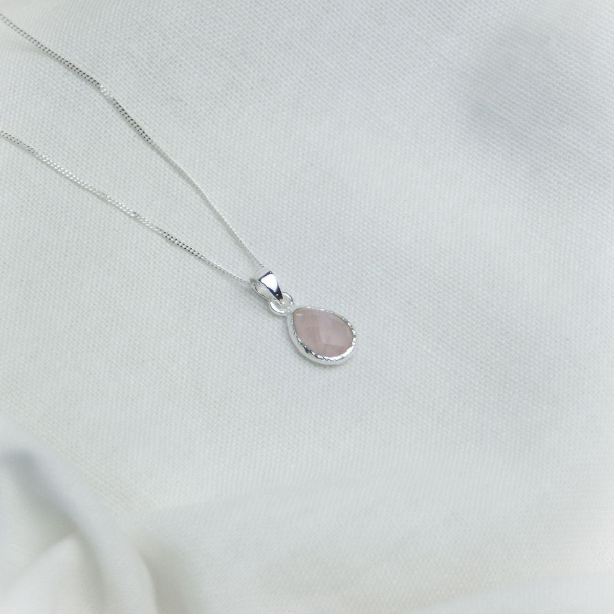 a pink pendant necklace on a white cloth