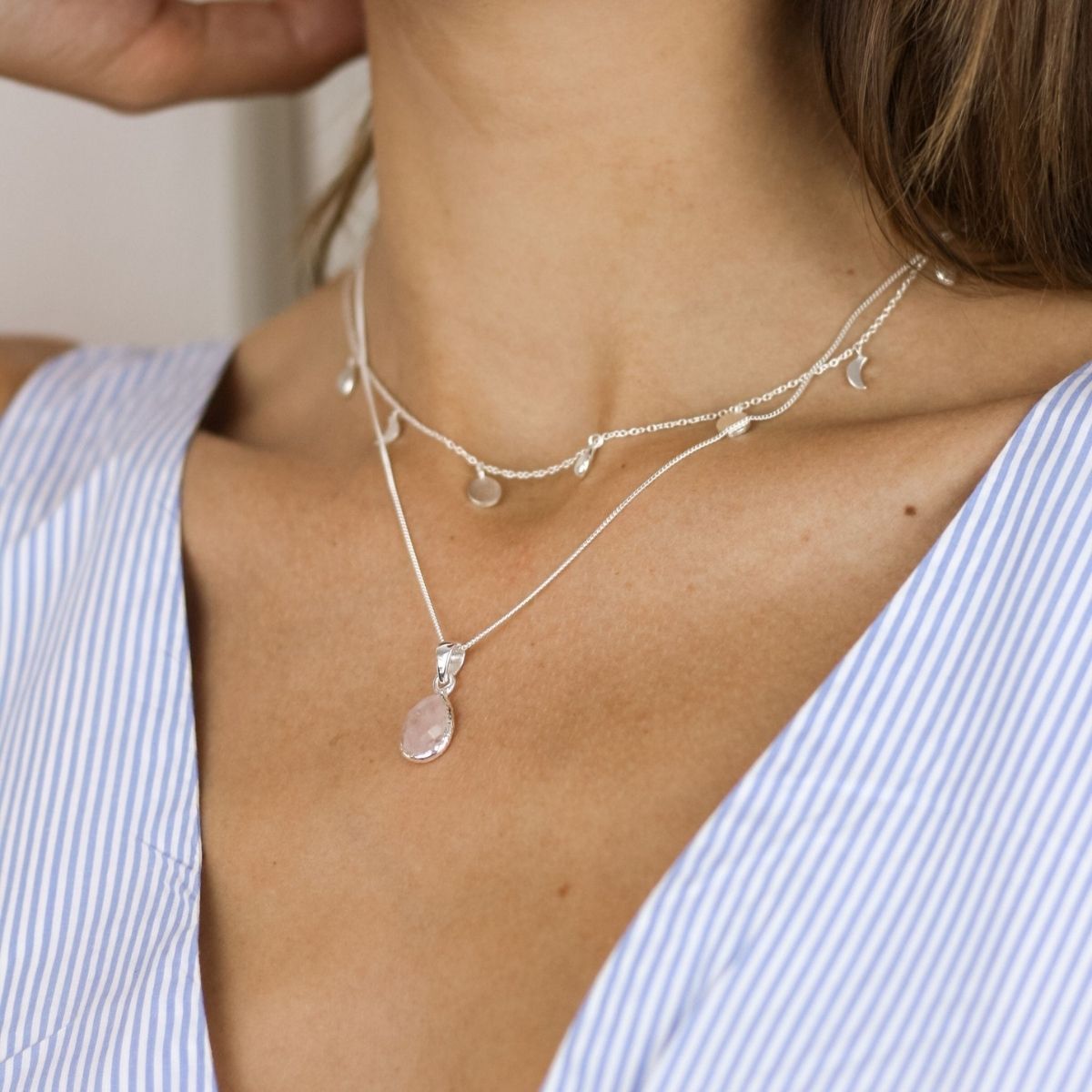 a woman wearing two necklaces around her neck