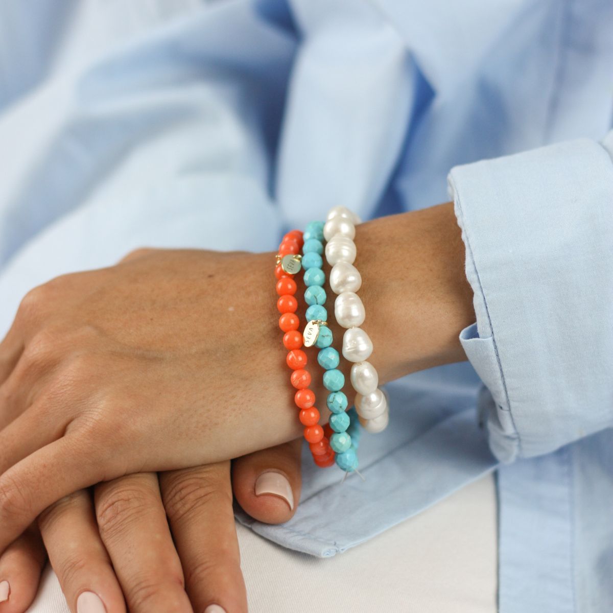 a woman wearing stacked bracelets on her arm