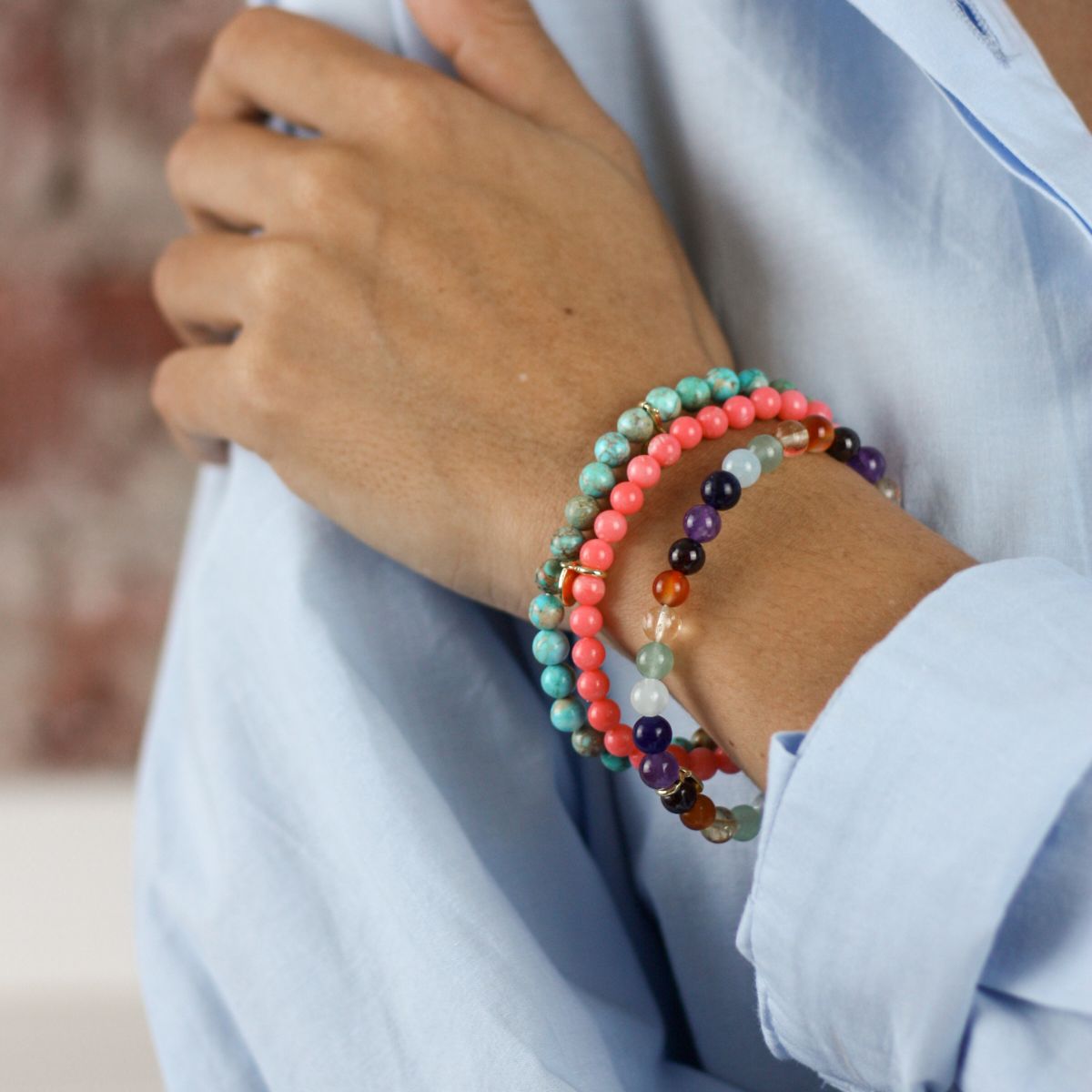 a woman wearing a stacked stone bracelets on her wrist