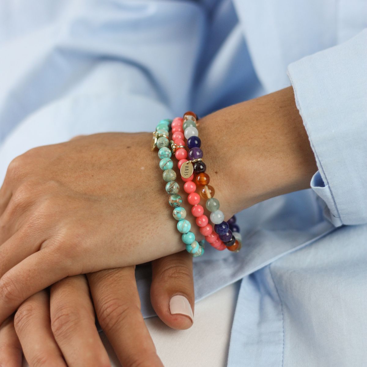 a woman wearing a stacked stone bracelets on her wrist