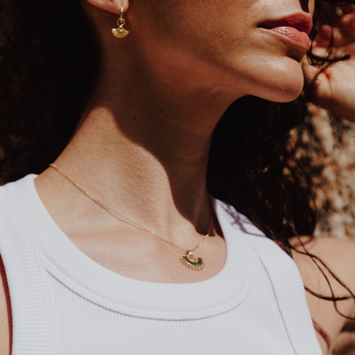 a woman wearing fan shaped necklace and earrings