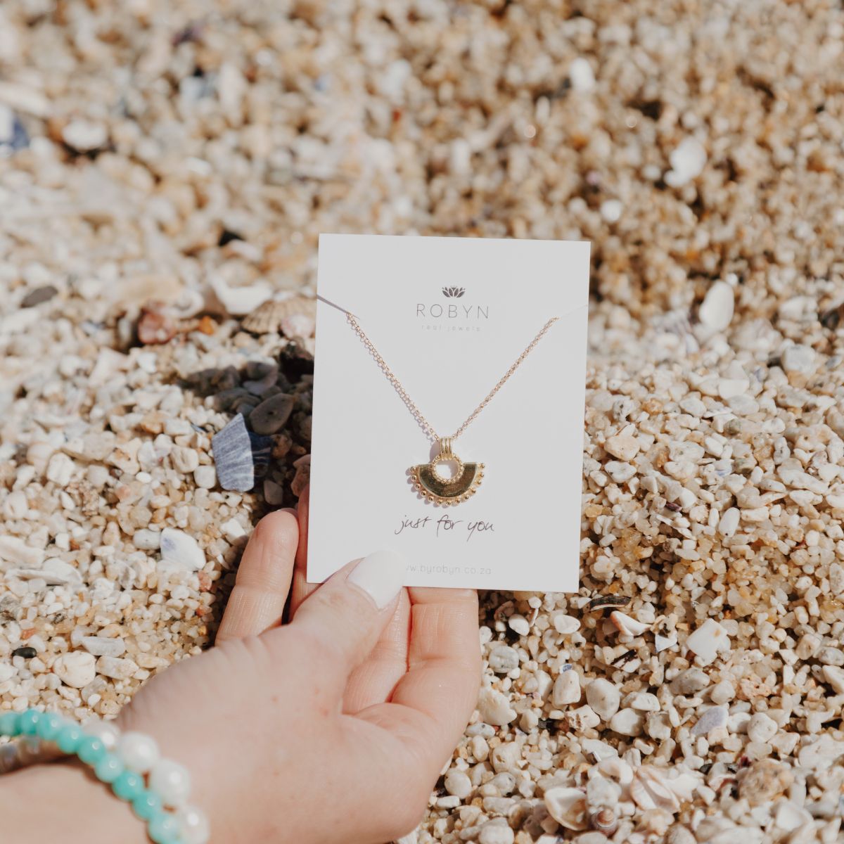 a woman holding a card with a fan shaped necklace around it 